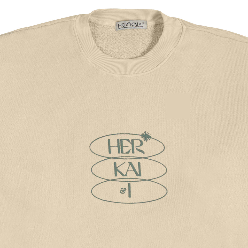 DETAIL VIEW OF HER KAI & I LOGO ON FRONT OF BOUNDLESS IN DIVINITY CREWNECK - BY HER KAI & I KYRIE